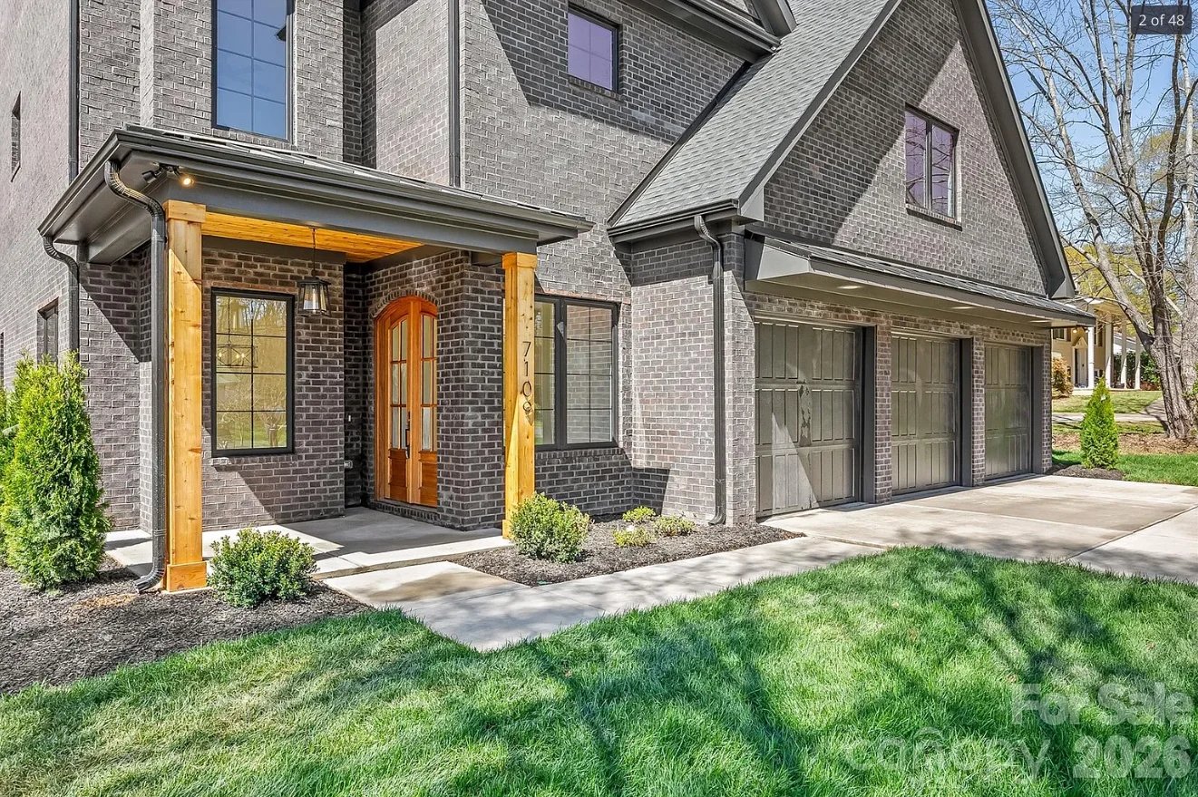 Modern brick home exterior with yellow-framed entryway, patio, and manicured lawn landscaping